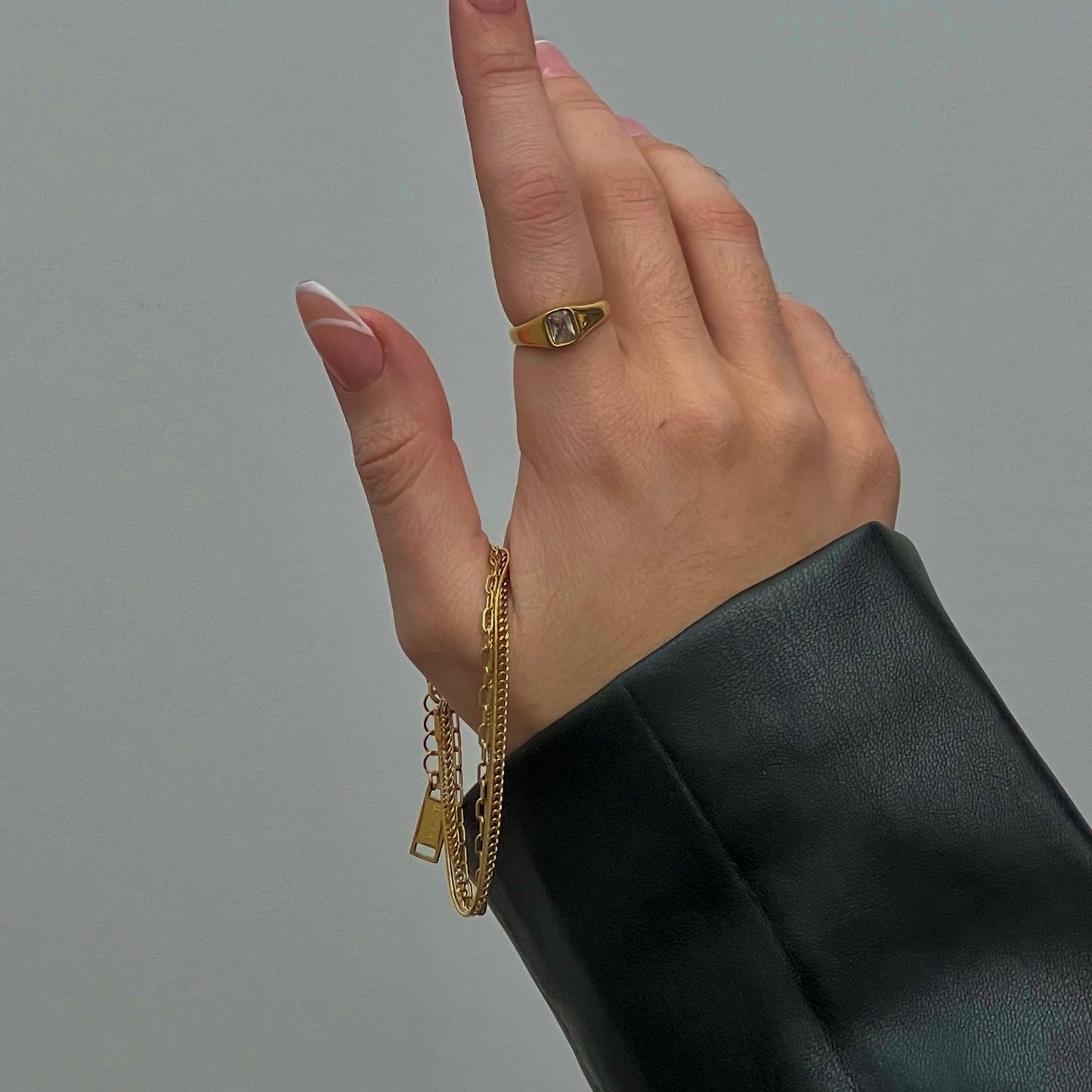 hand holding a gold bracelet containing 4 different chain designs layered into one bracelet