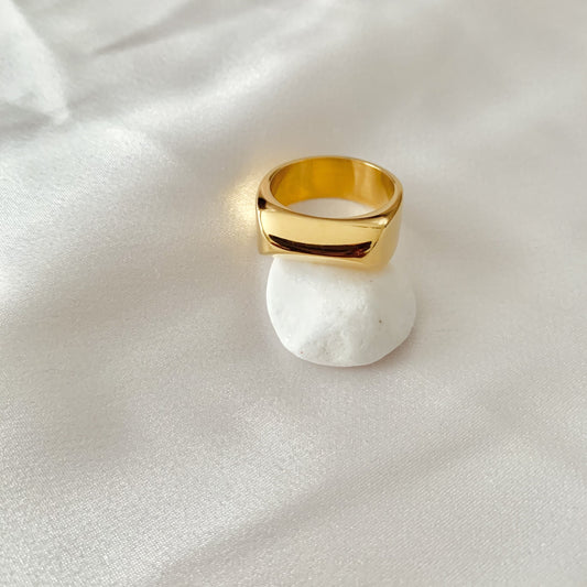 Gold ring on a white stone with a white fabric background
