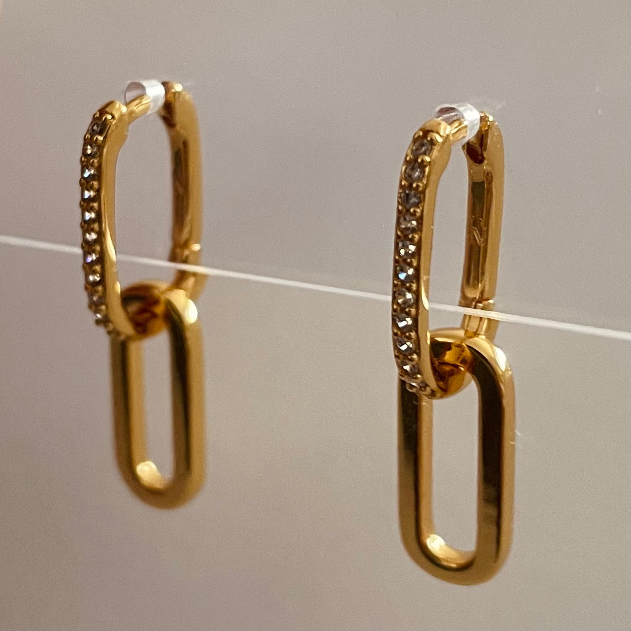 Gold hoop earrings with embedded stones on a gray background