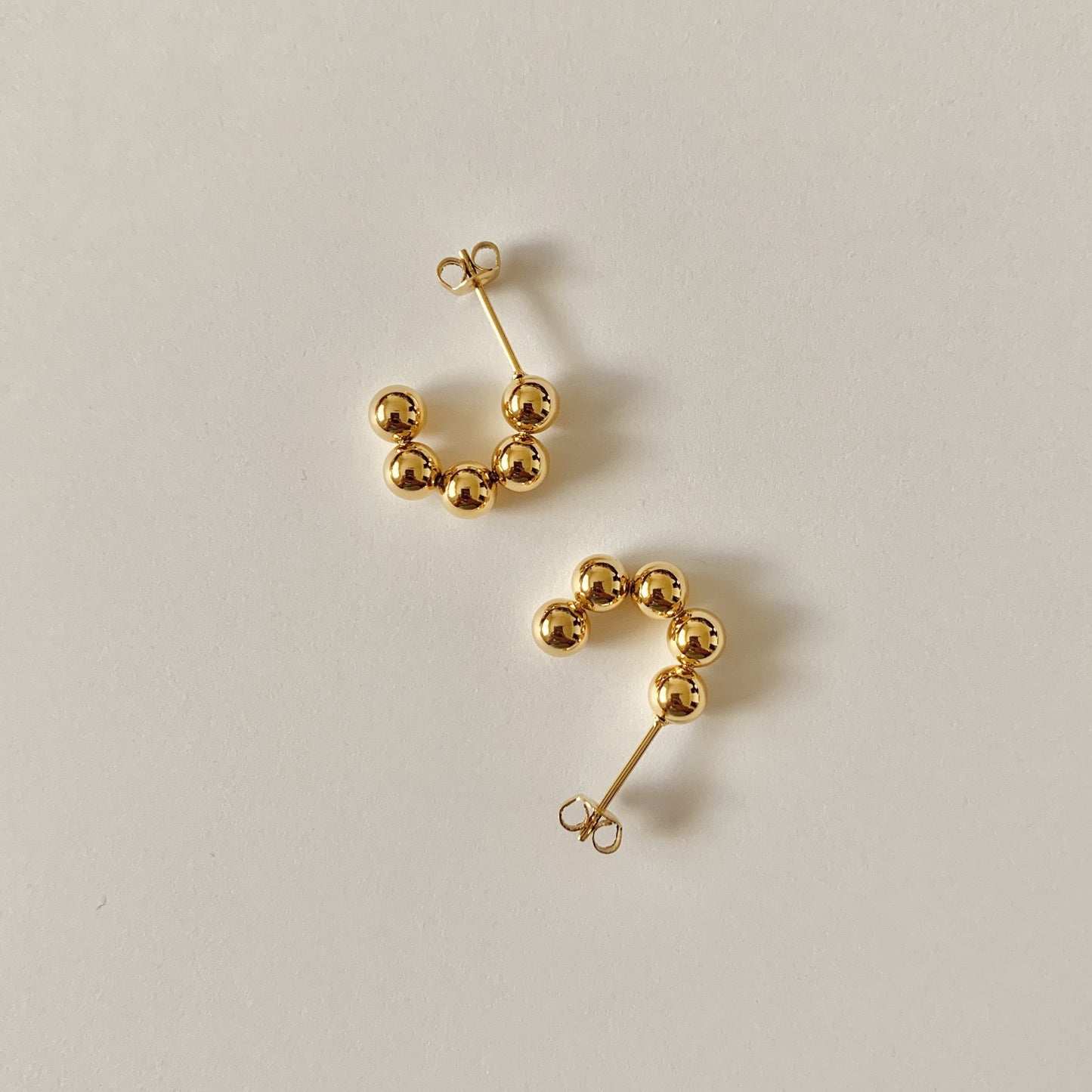 Pair of gold beaded earrings on a light gray background