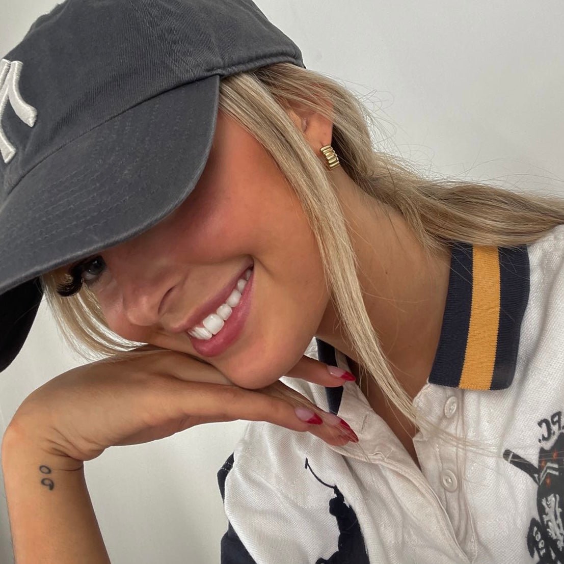 Woman wearing a gray cap and white shirt with gold ribbed earrings from daurielle.