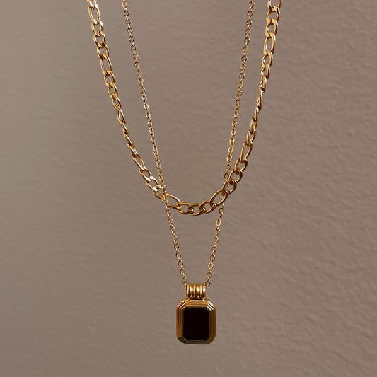 2 layered gold necklace (one thicker chain and one thinner with  gold pendant with a black square stone in the middle suspended rom the thinner chain