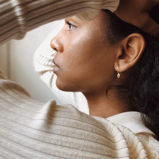 Woman wearing gold hoop earrings with clear teardrop shaped charms.
