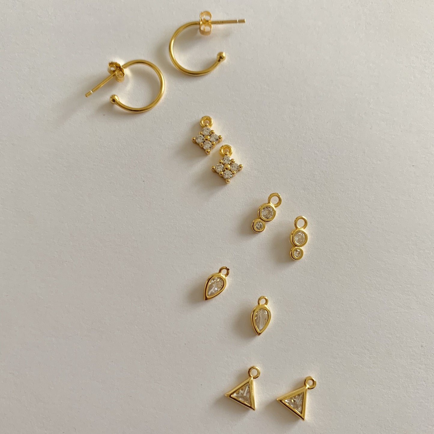 Collection of gold earrings on a light gray background