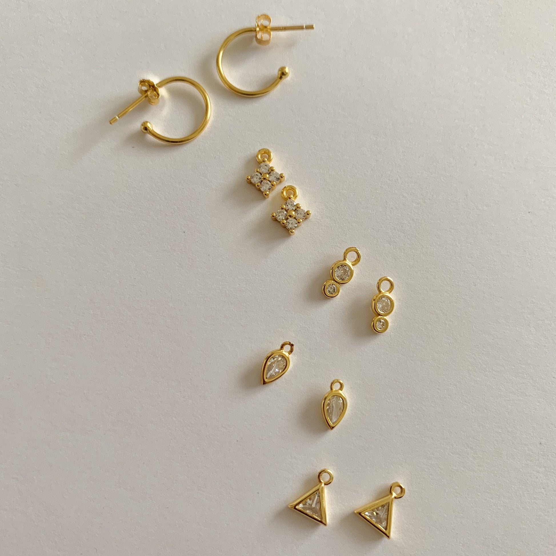 Collection of gold earrings on a light gray background