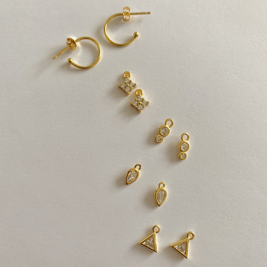Collection of gold earrings on a light gray background