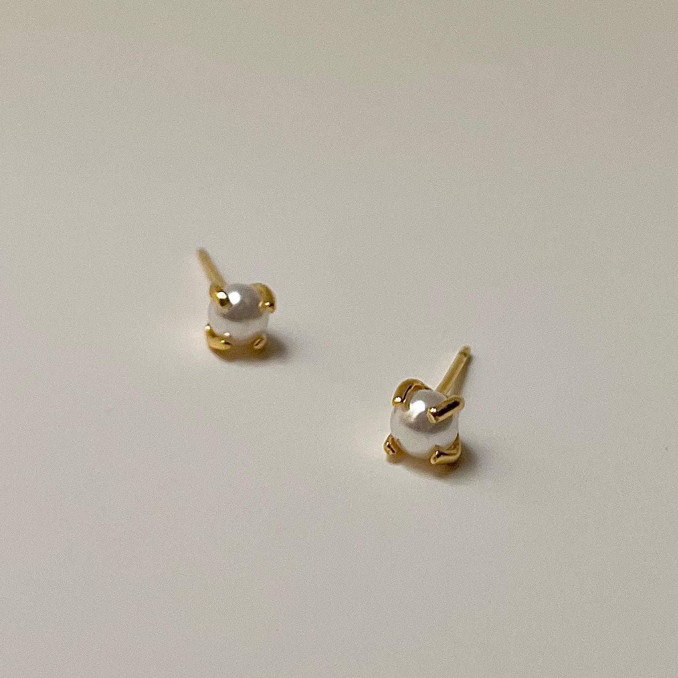 Pair of pearl stud earrings with gold posts on a light gray background